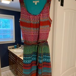Bright colored pattern dress with tan belt.